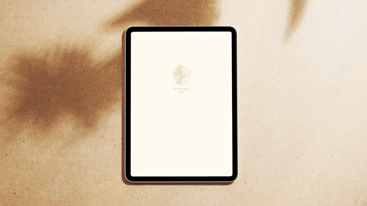 YOHAKU edit Dated Daily Planner, Kinari Edition — its warm undyed white cover resting flat, with soft leaf shadows
