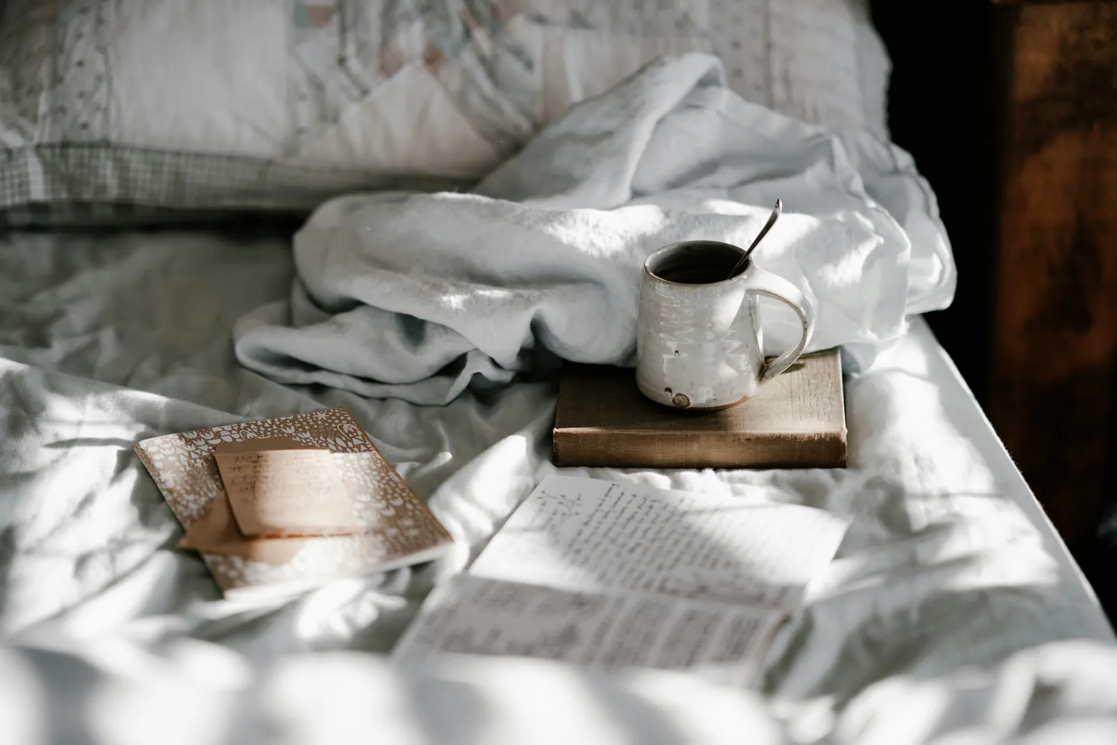 A quiet cup of coffee and a notebook on linen sheets in soft morning light