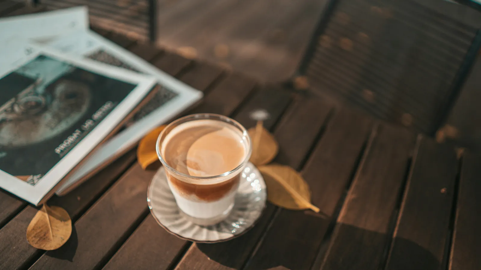 A glass of coffee beside scattered photographs on a wooden table