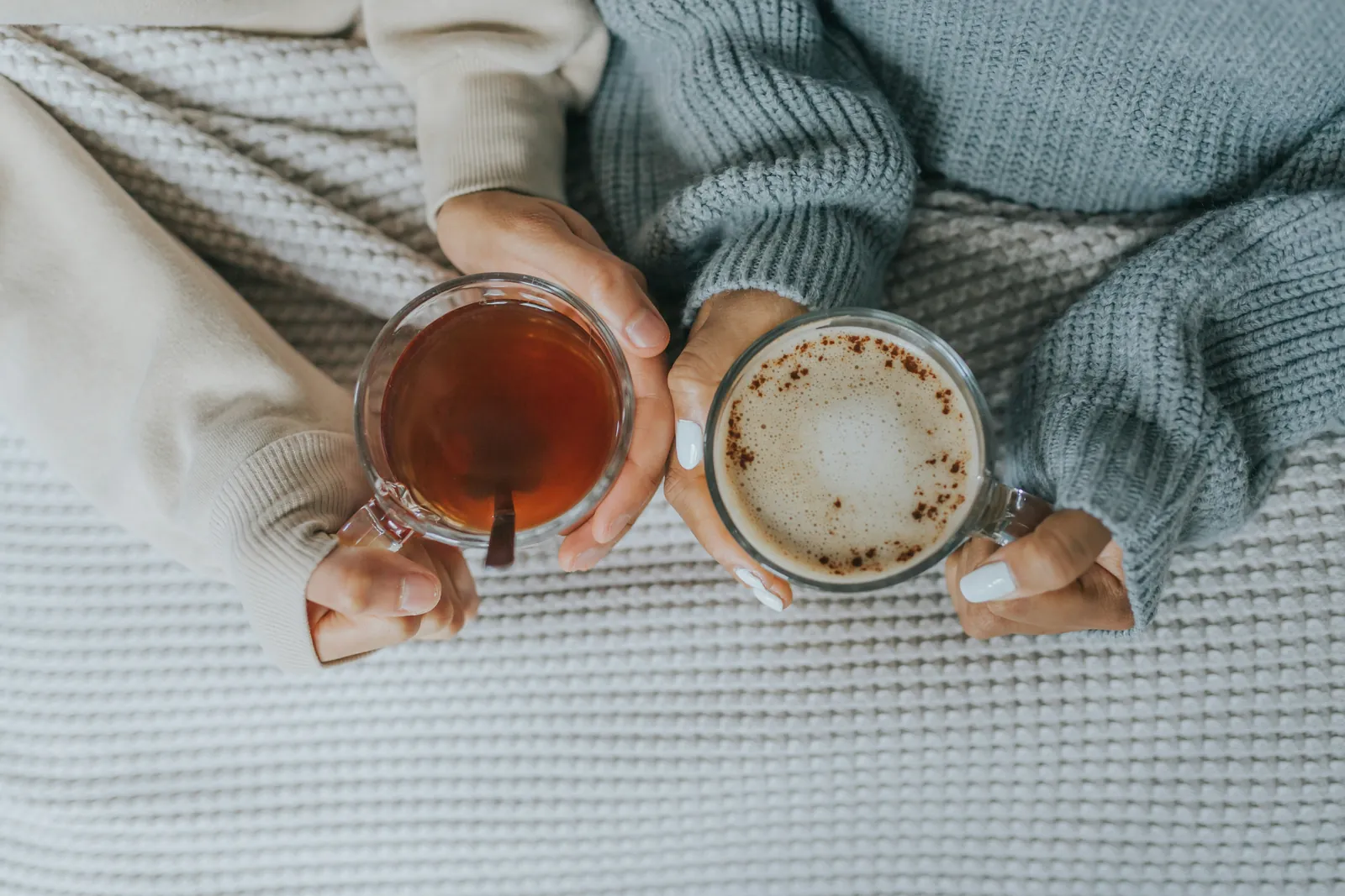 Two warm cups held over a soft knitted blanket