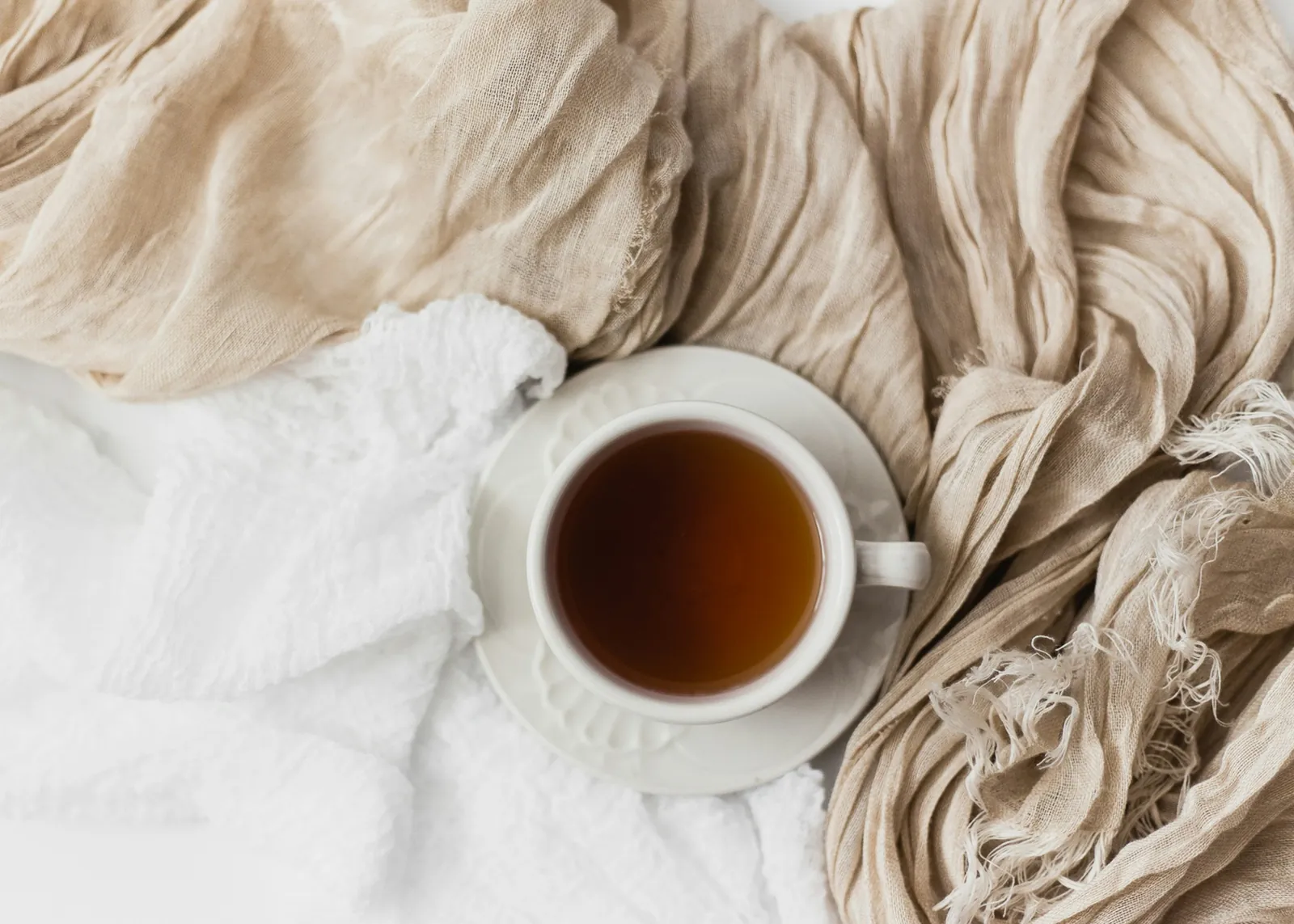 A cup of tea set down on soft linen